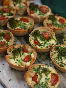 Mini Tortilla Quiches with crispy tortilla bases filled with mozzarella, cherry tomatoes, and broccolini.