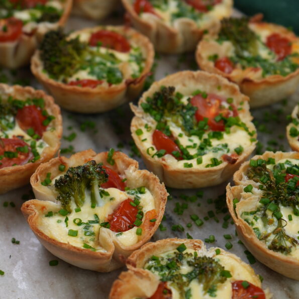 Mini Tortilla Quiches with crispy tortilla bases filled with mozzarella, cherry tomatoes, and broccolini.