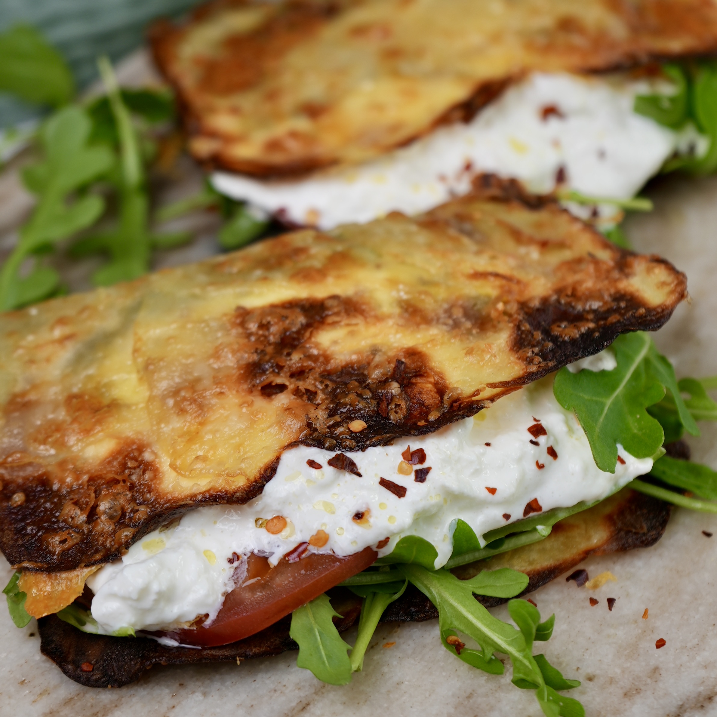 Crispy potato wrap filled with creamy burrata, fresh rocket, tomato slices, and vibrant pesto.