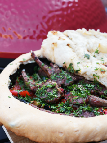 Grilled lamb chops and vegetables enclosed in golden-brown savoury dough, served in a cast-iron skillet.