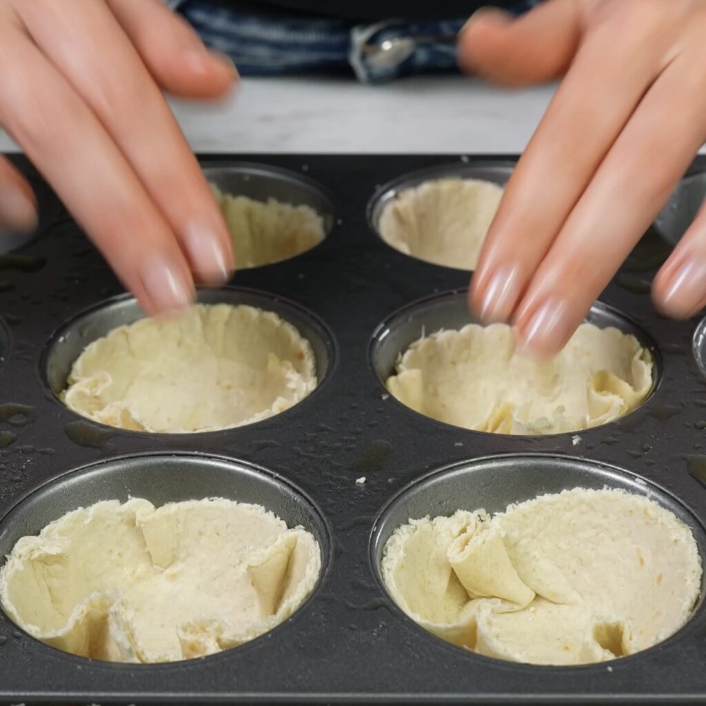 Tortilla circles placed into muffin tins to form bases for mini quiches.