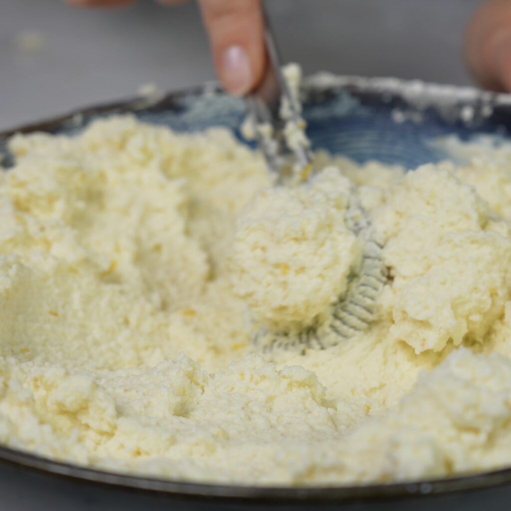 Mixing ricotta cheese with icing sugar, lemon zest, and vanilla extract in a bowl.