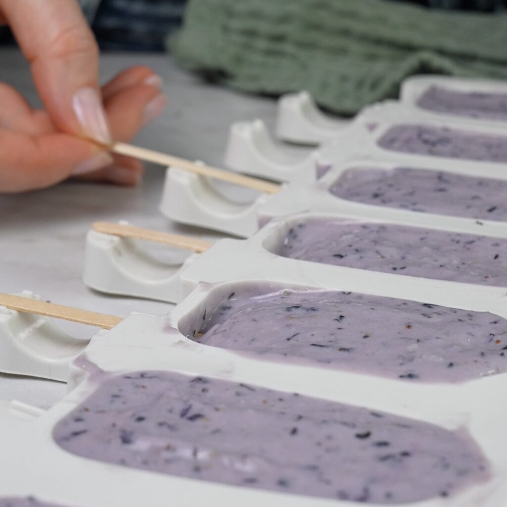 Ricotta blueberry mixture in a popsicle mould with a wooden stick is inserted.