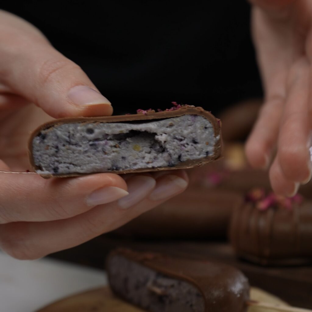 Frozen blueberry ricotta pop sliced in half, revealing a creamy blueberry filling inside.