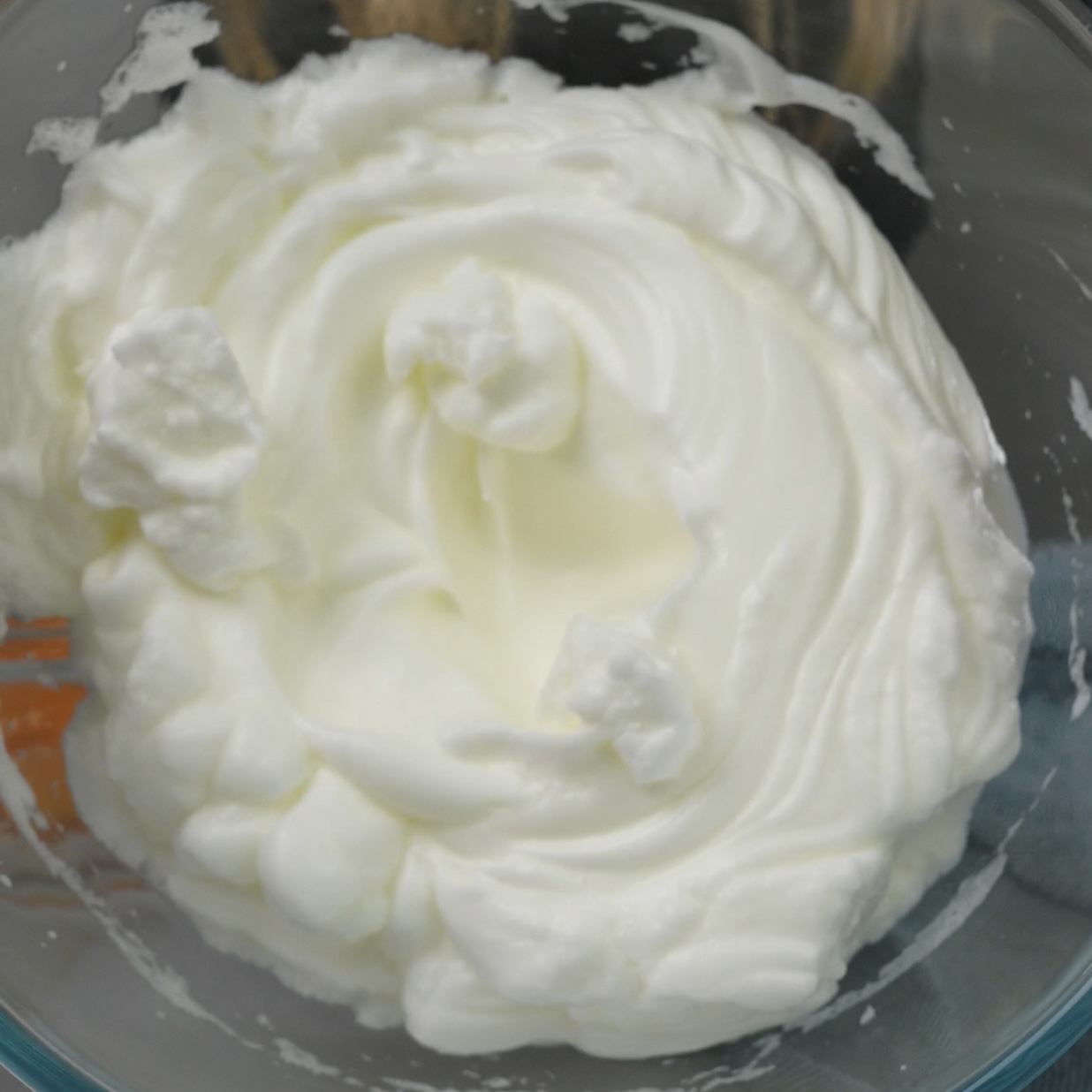 Egg whites whisked into firm peaks in a mixing bowl.