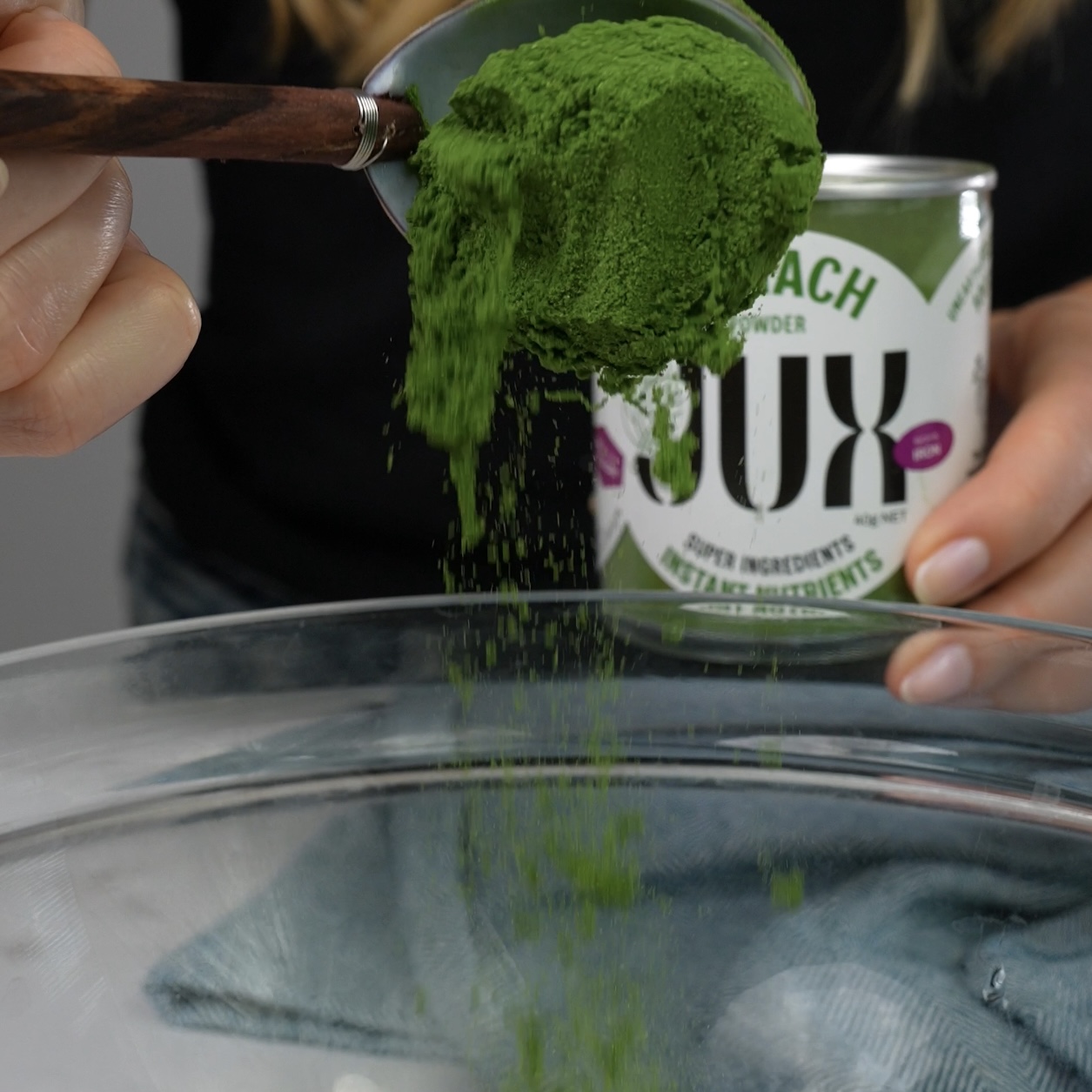 Adding spinach powder to egg yolks in a mixing bowl.