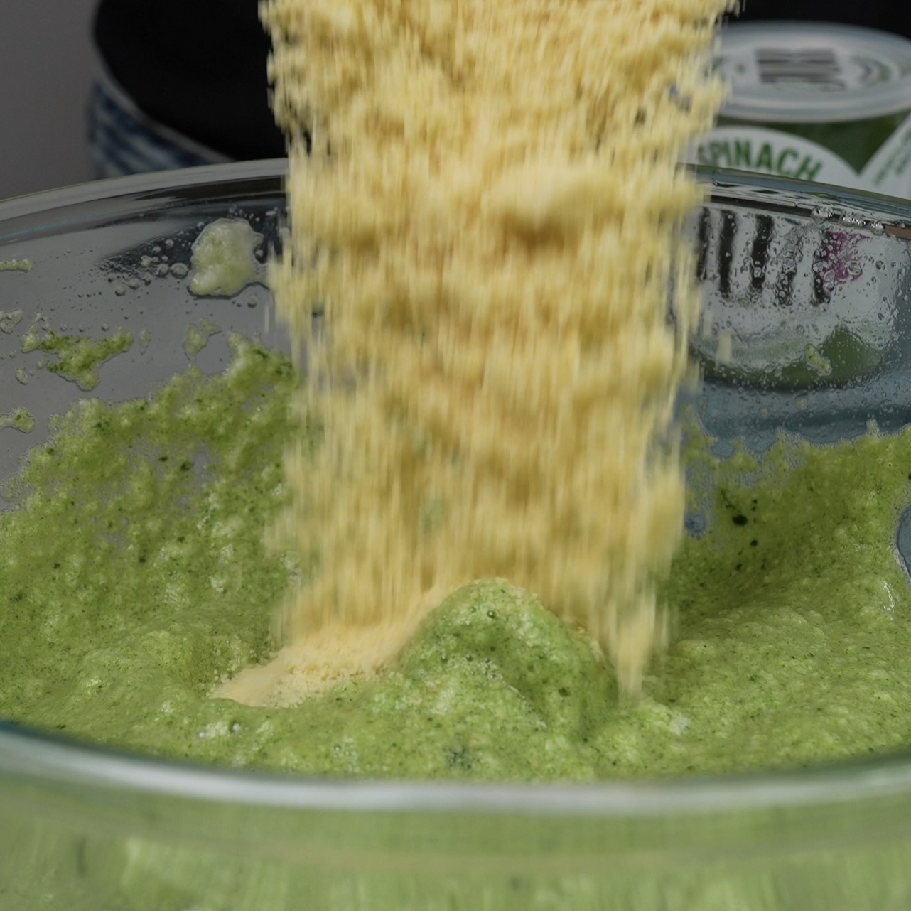 Almond flour being added to a bowl of mixed ingredients.