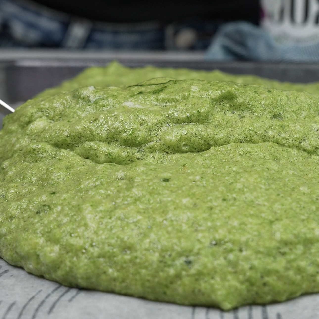 Spreading spinach roll mixture evenly on a baking tray lined with parchment paper.