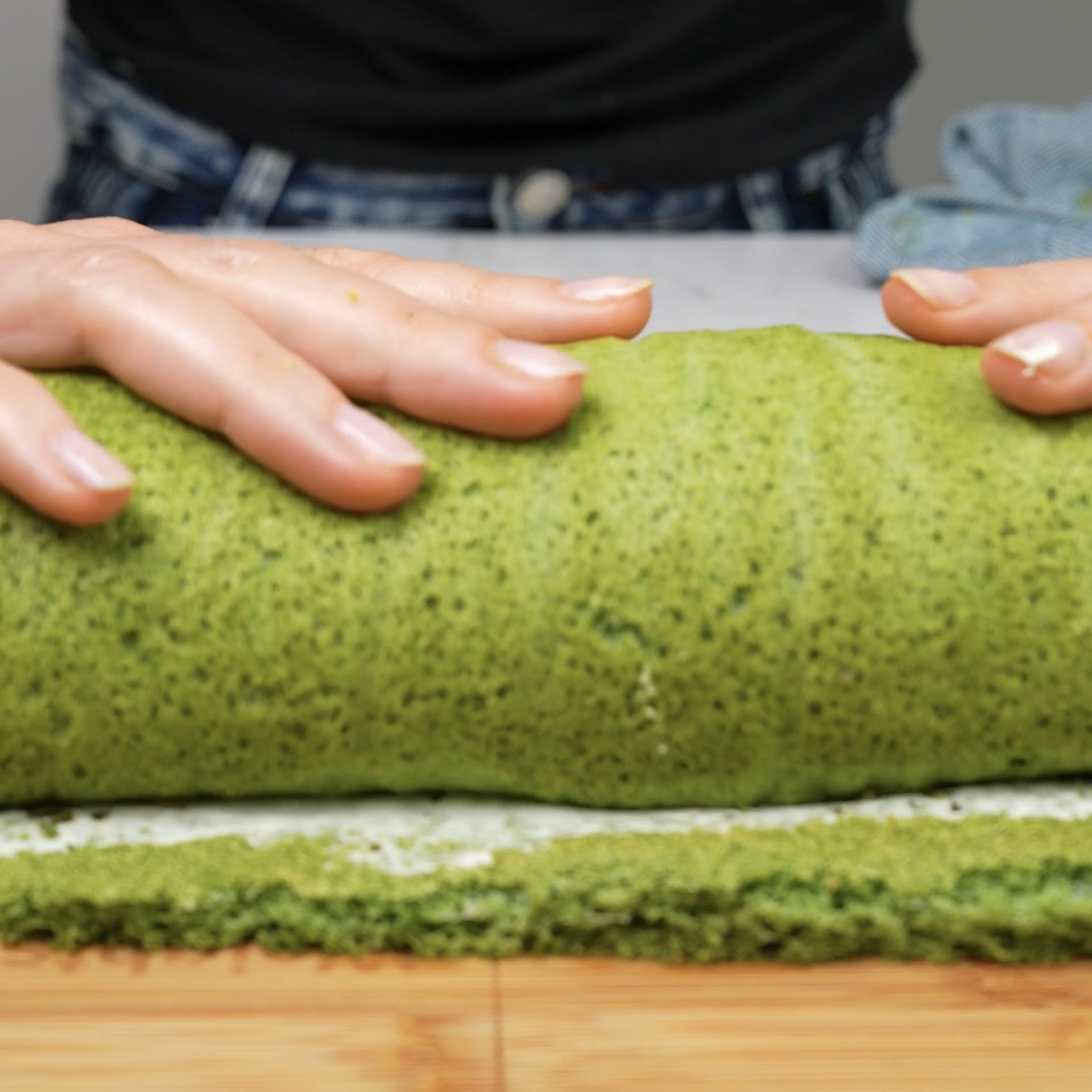 Rolling the spinach chopped salad roll tightly from one end.