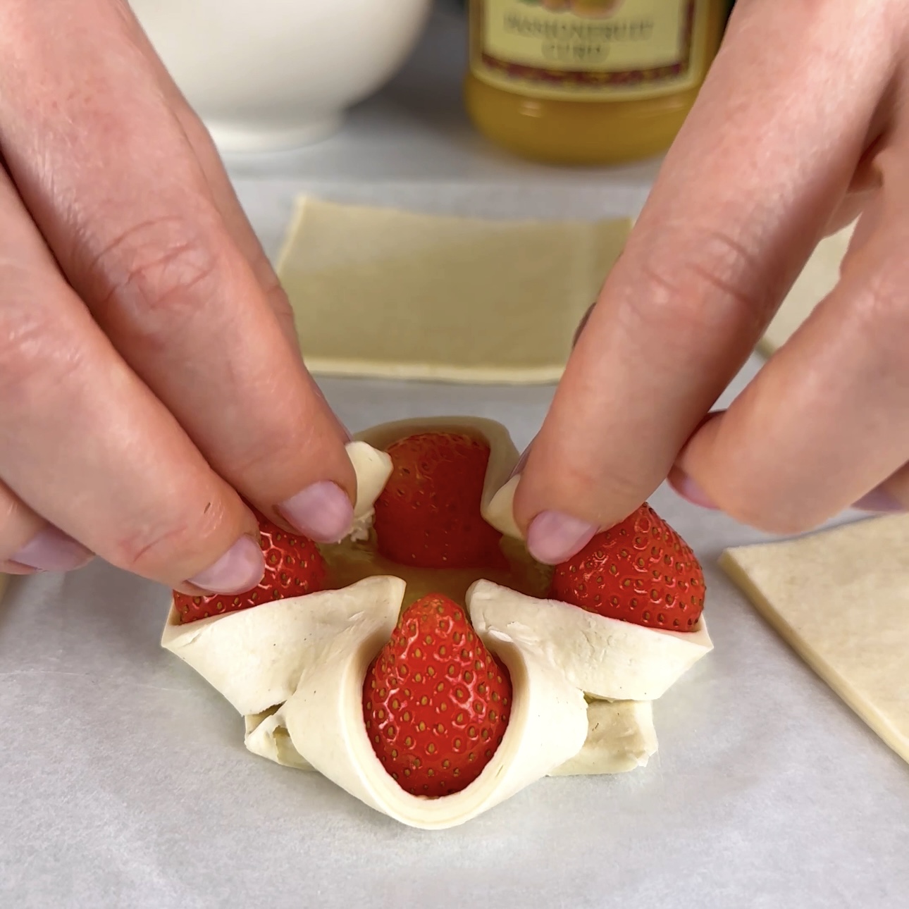 Folding the outer corners of puff pastry squares to meet in the centre.