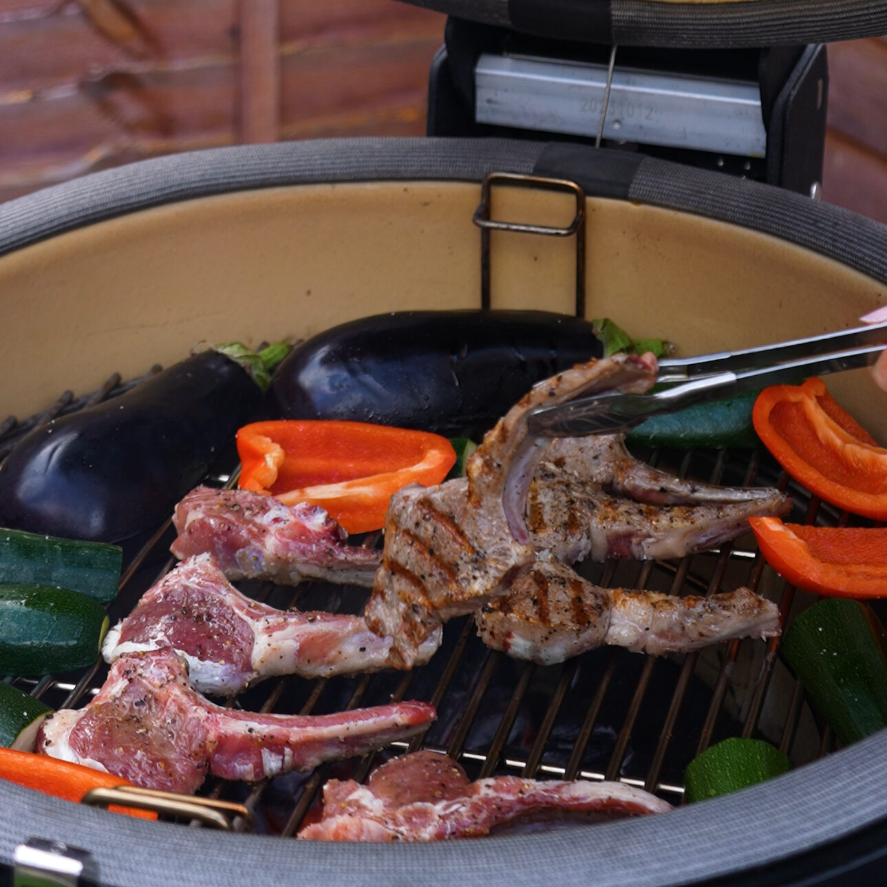 Lamb chops sizzling on the grill, with smoke rising and grill marks visible.