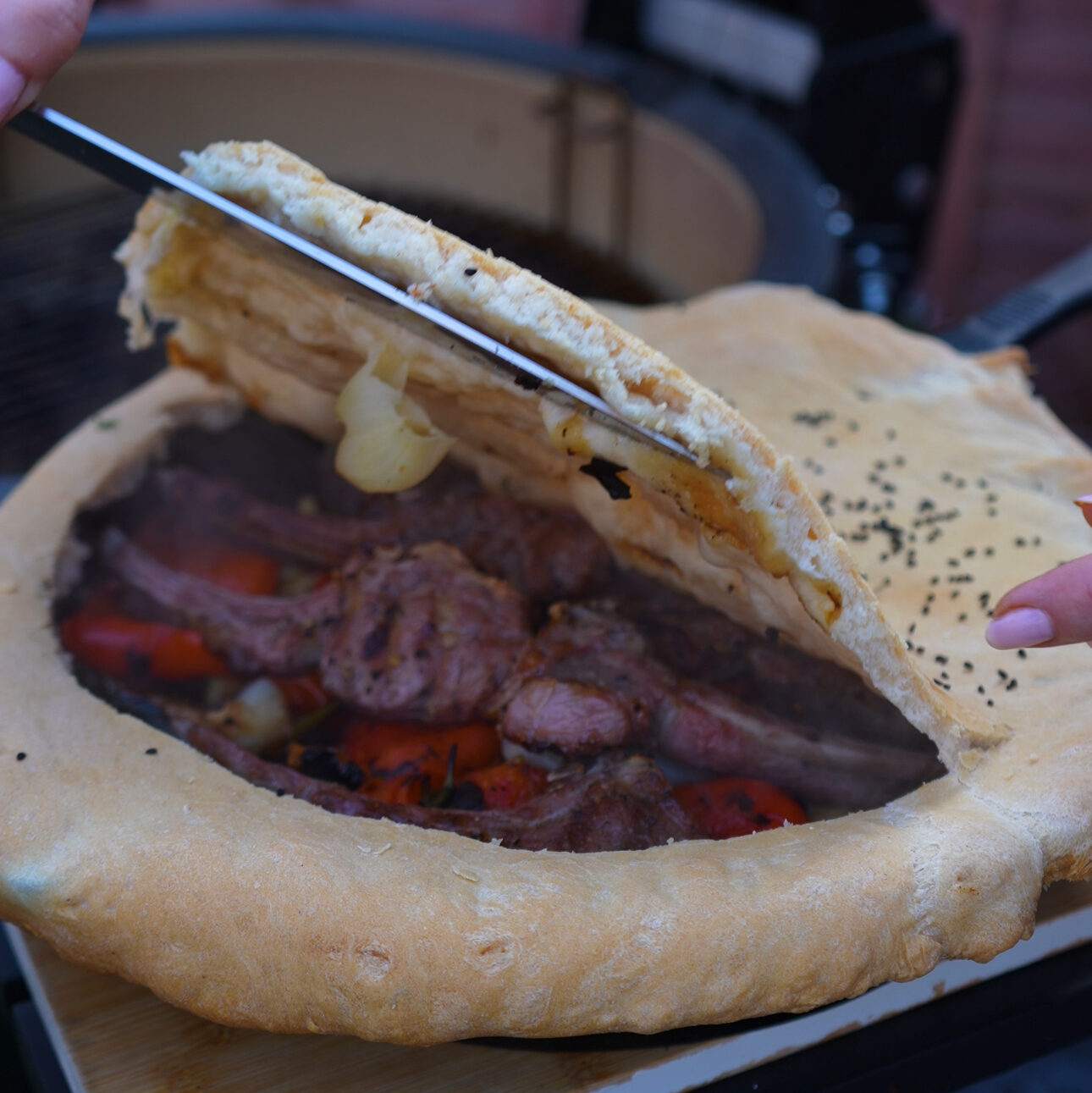 Baked cast-iron skillet with a golden-brown crust, scored to reveal the lamb chops and vegetables inside.