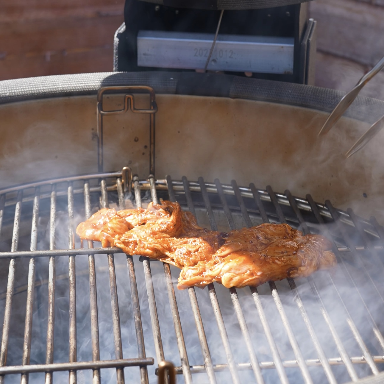 Chicken thighs being placed on the grill presentation side down.