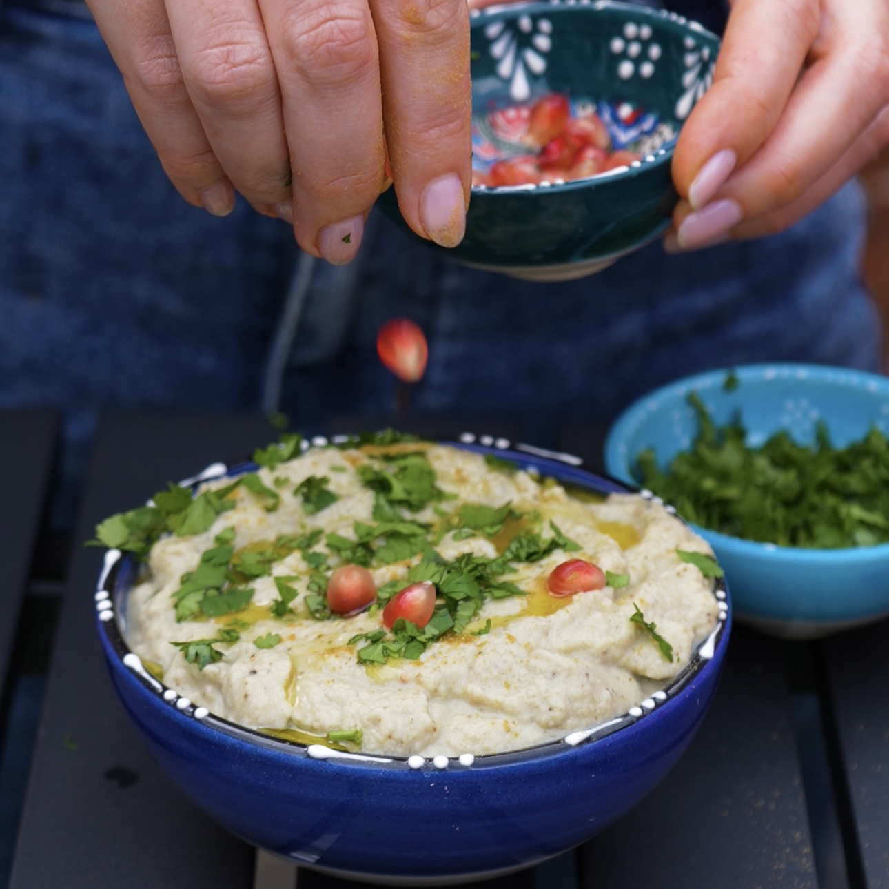 Adding pomegranate seeds as a garnish on top of baba ganoush.