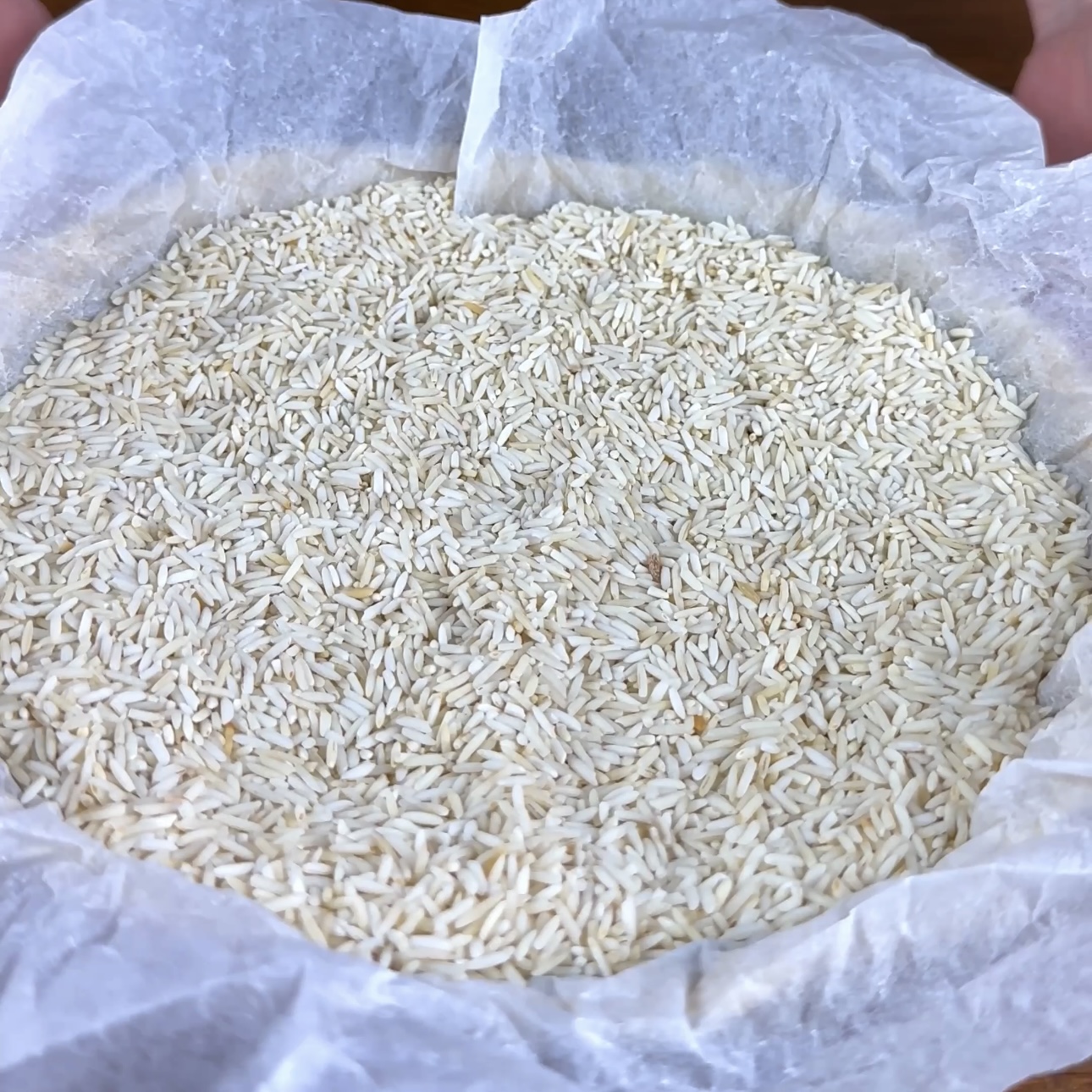 A photo of a pastry case lined with baking paper and filled with dried rice, ready for blind baking.