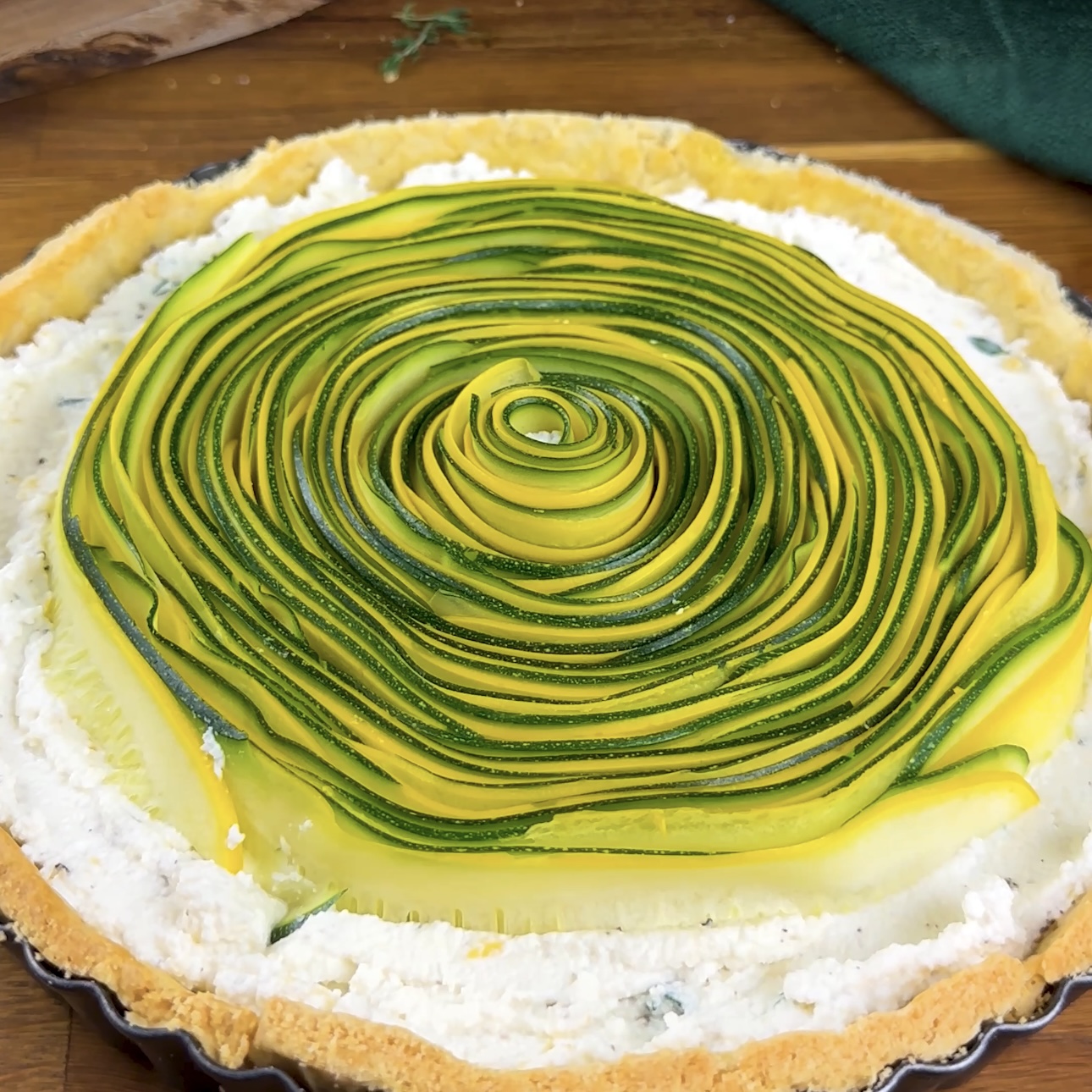 A photo of remaining courgette strips arranged around the rolled courgette strips in a tart case.