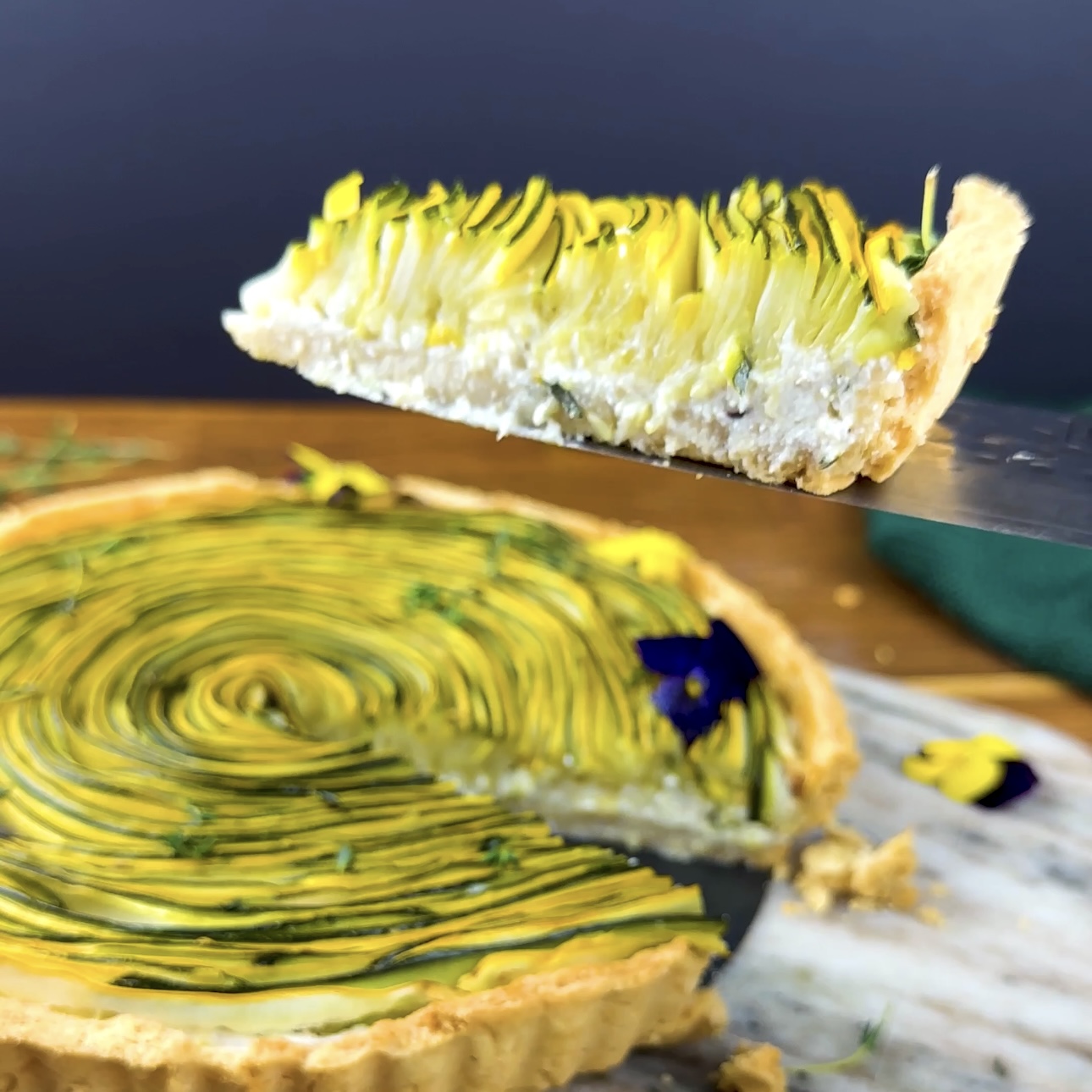 A sliced piece of Courgette Ricotta Tart, showing the creamy filling and colorful vegetable strips.