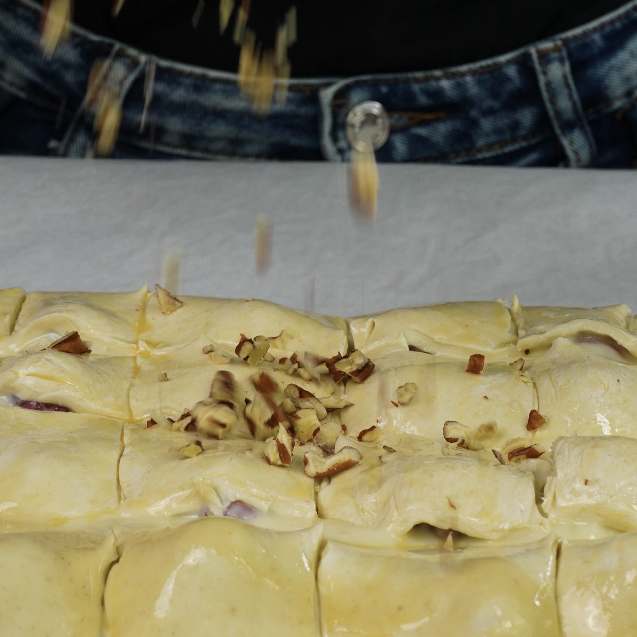 Chopped walnuts being sprinkled over pastry.