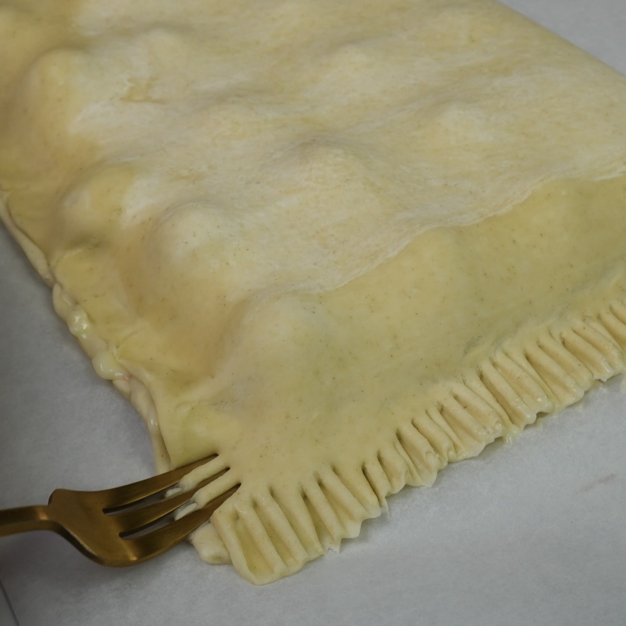 Edges of the pastry being sealed with a fork.