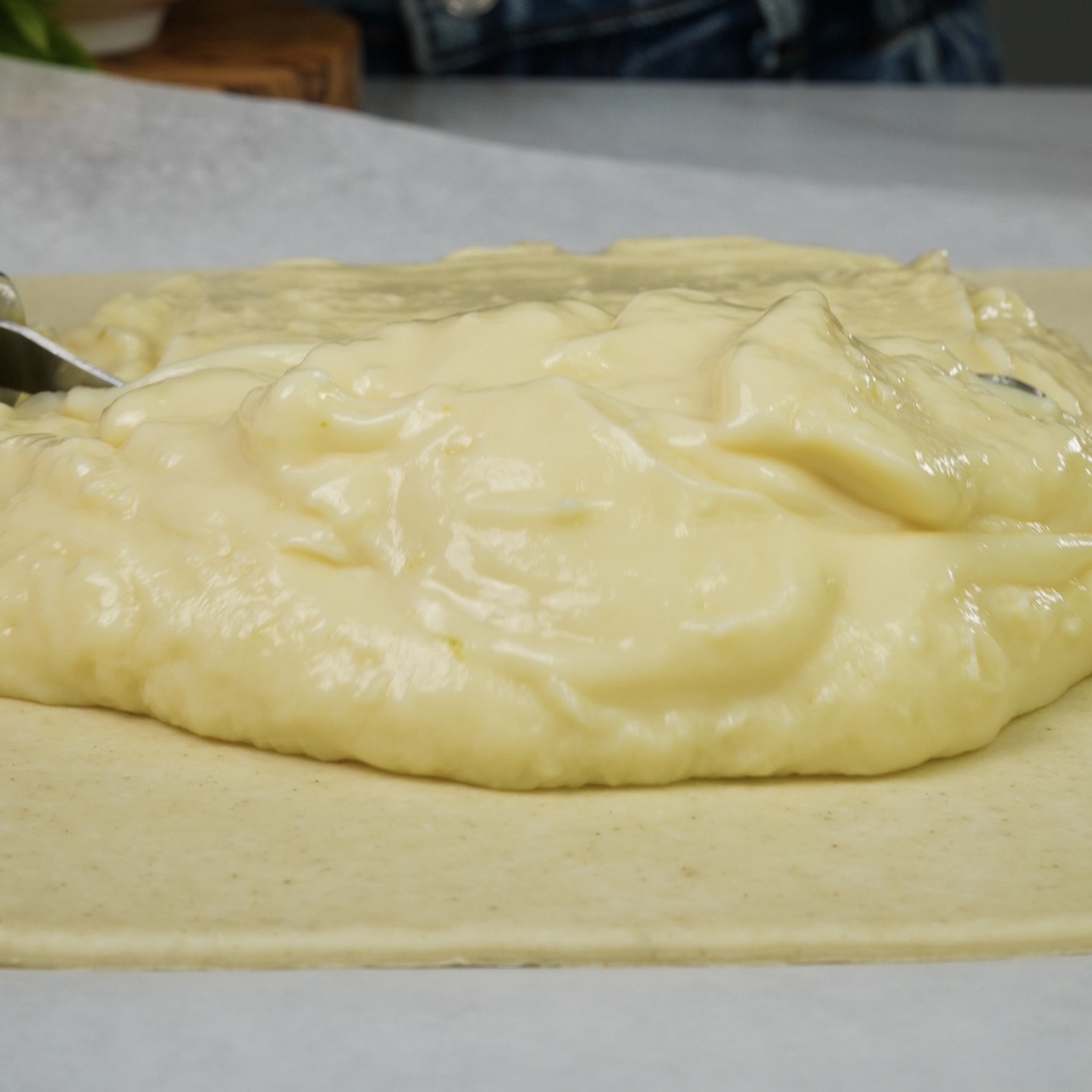 Spreading creamy custard evenly over puff pastry.