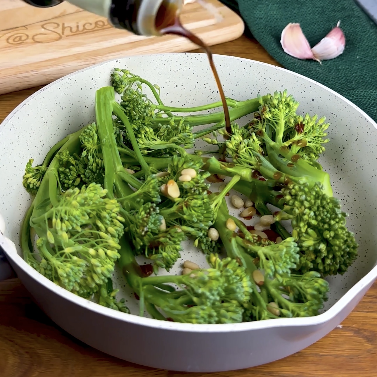 Fresh long-stemmed broccoli and pine nuts, prepped and ready to be cooked in a pan.