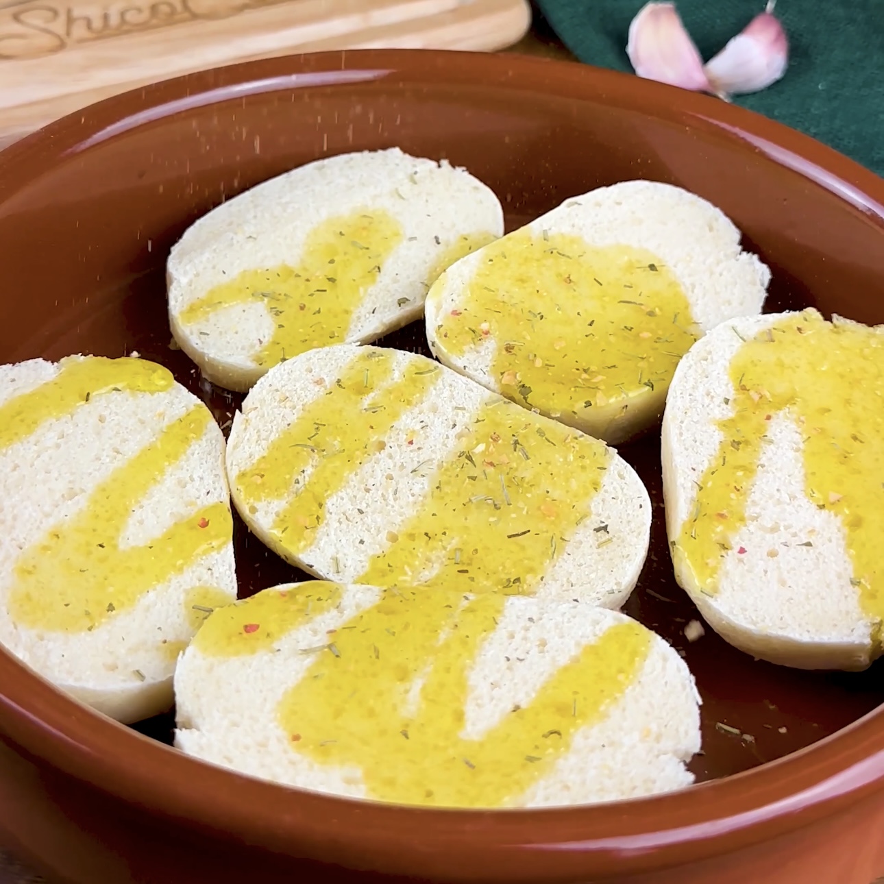 Part-baked bread rolls drizzled with olive oil and seasoned with Mediterranean spice mix, ready to be baked.