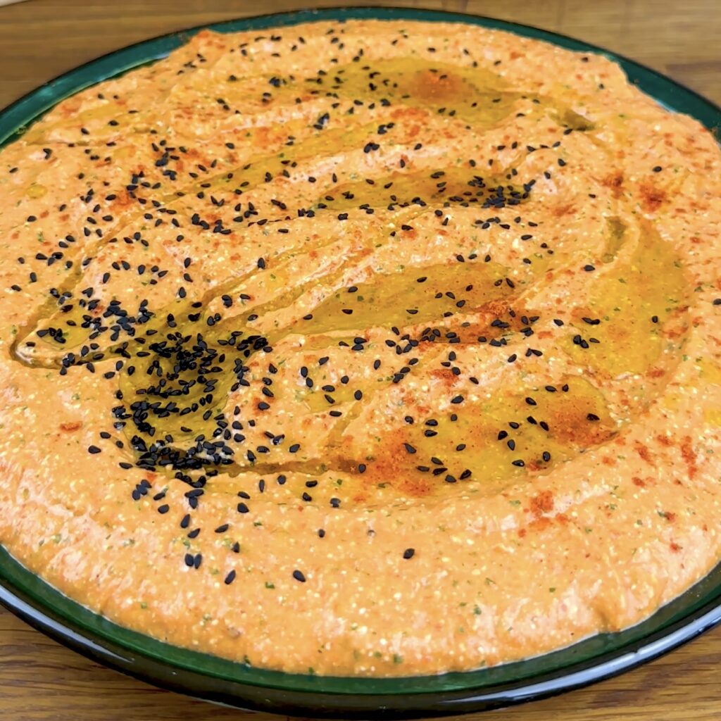 Nigella seeds are sprinkled over a bowl of Roasted Red Pepper and Feta dip.