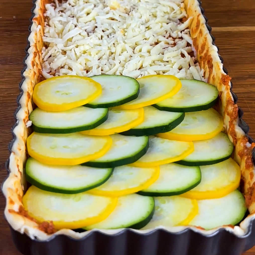 Courgette slices arranged on top of cheese on a tart.