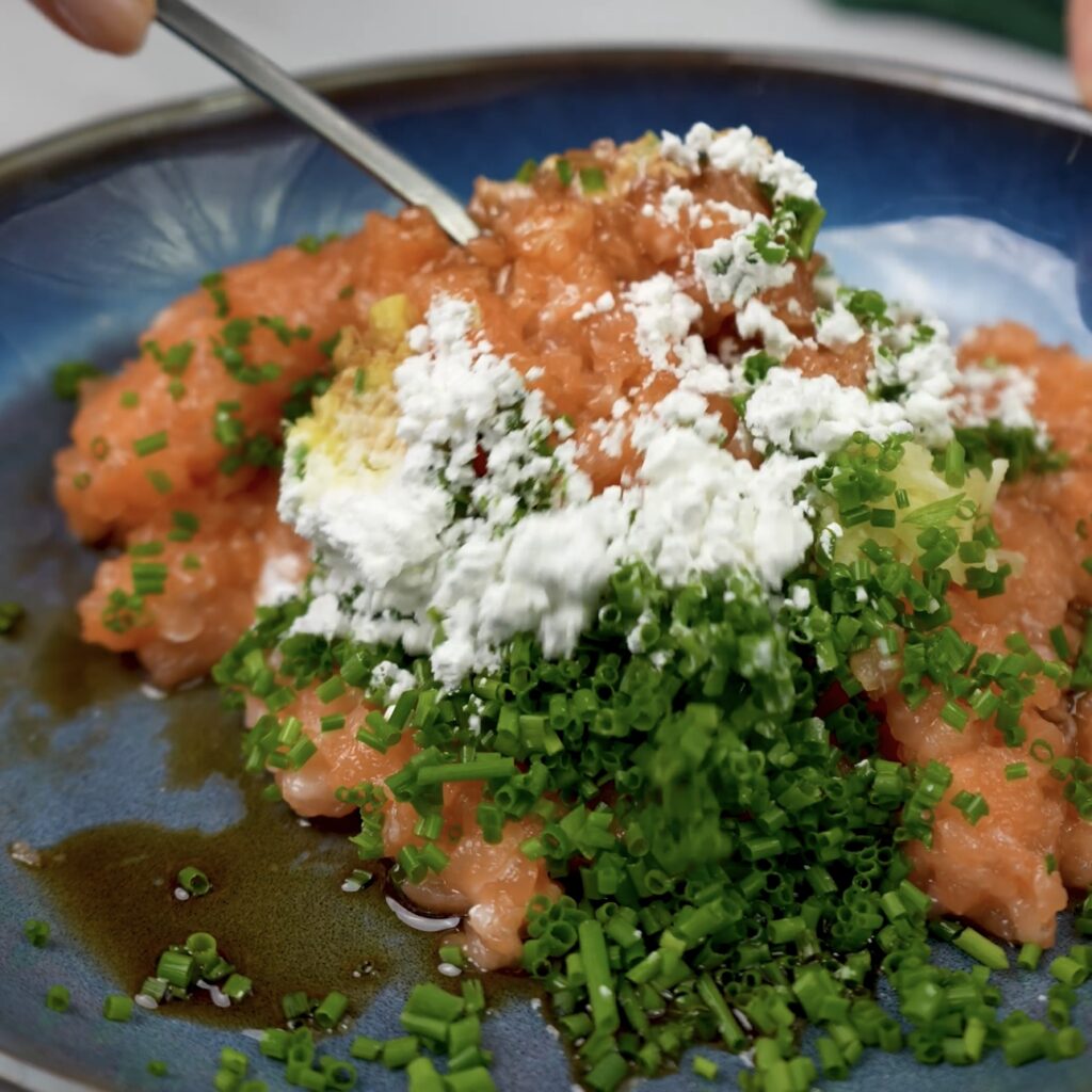 Mixing salmon filling with garlic, ginger, chives, and seasoning in a bowl