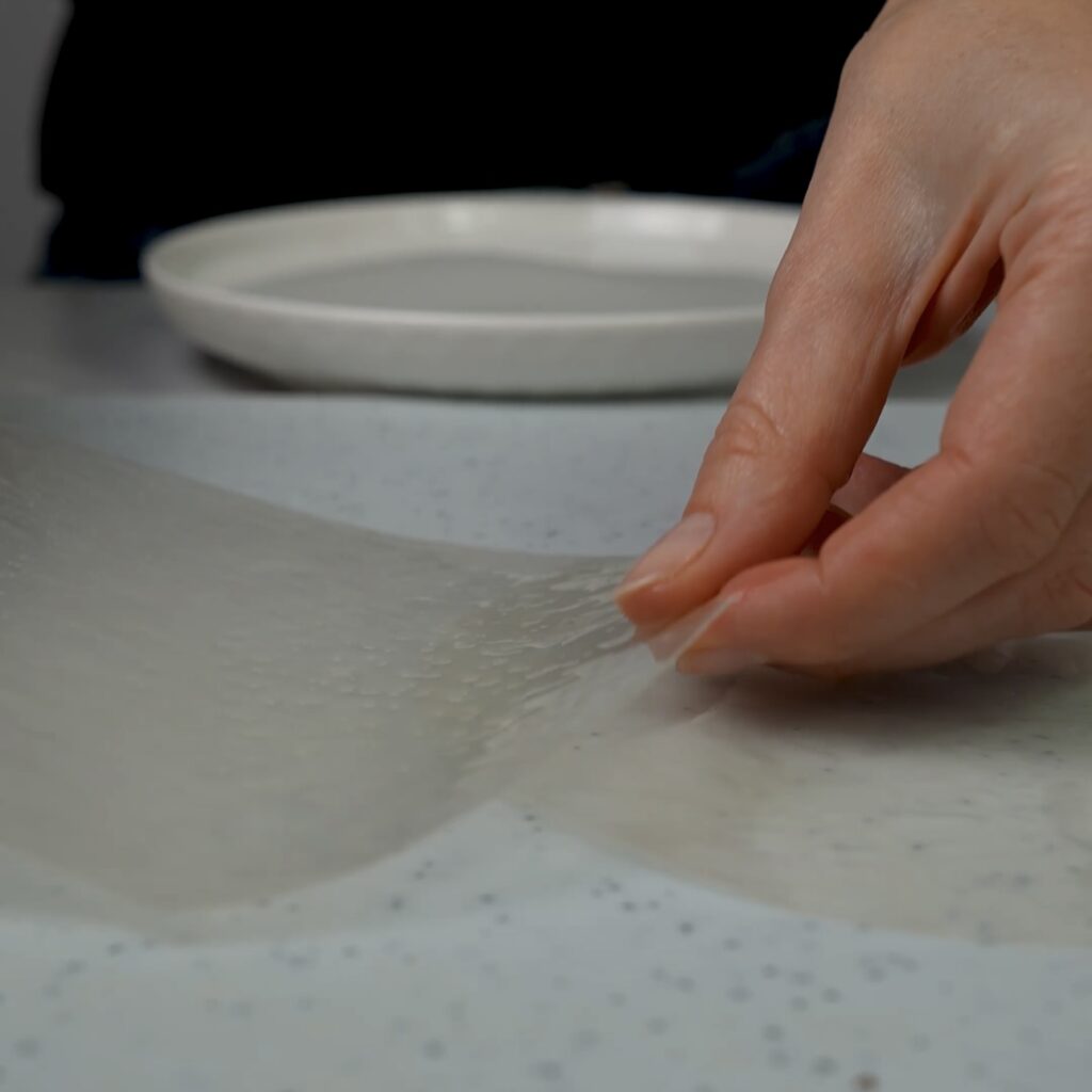 Overlapping soaked rice paper sheets on a working surface