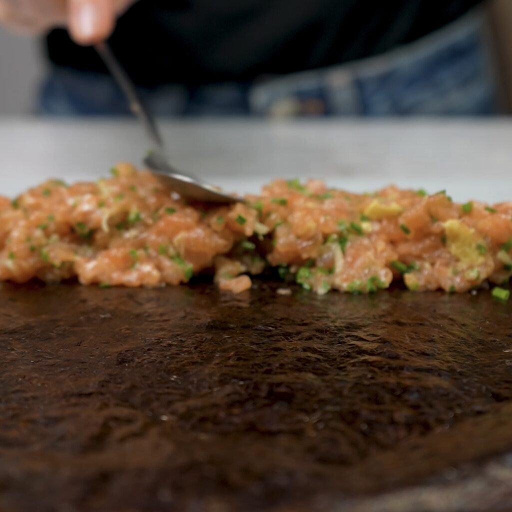 Spreading salmon filling on top of nori sheet