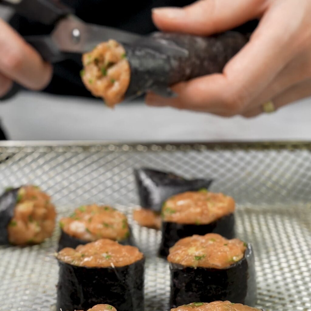 Cutting rolled salmon and nori into bite-sized pieces