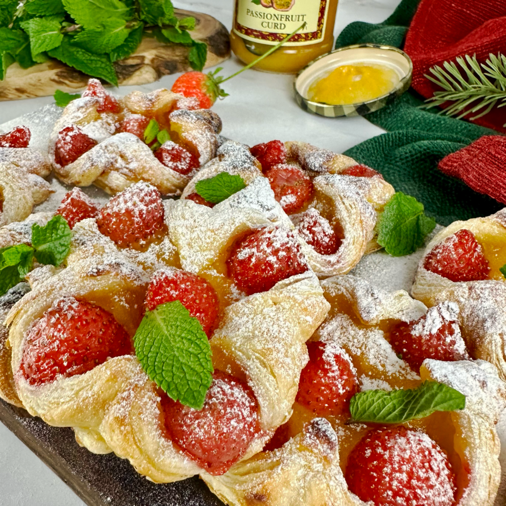 Passion fruit curd and strawberry puffs arranged on a plate, with a dusting of icing sugar and garnished with mint leaves.