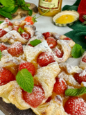 Passion fruit curd and strawberry puffs arranged on a plate, with a dusting of icing sugar and garnished with mint leaves.