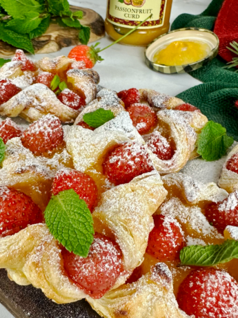 Passion fruit curd and strawberry puffs arranged on a plate, with a dusting of icing sugar and garnished with mint leaves.