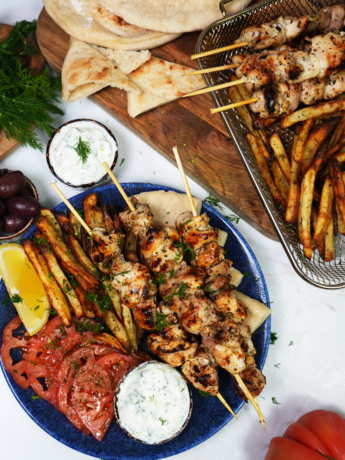 Greek chicken souvlaki skewers served on a plate with garnishes.