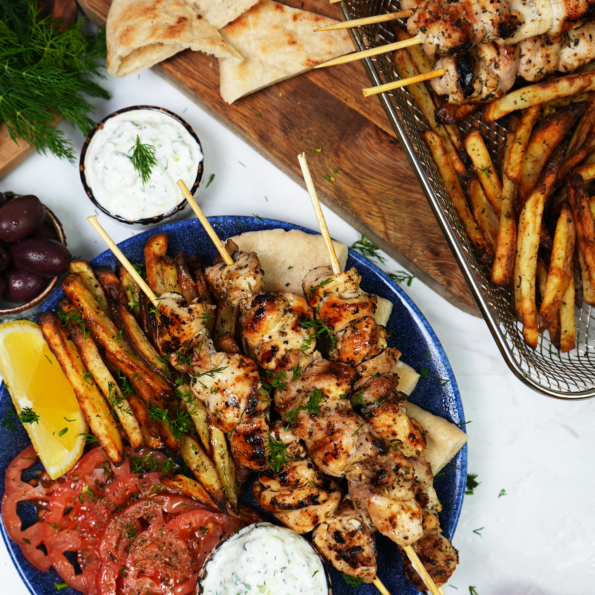 Greek chicken souvlaki skewers served on a plate with garnishes.