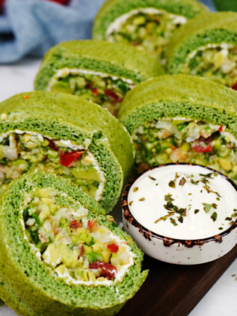 Spinach Chopped Salad Roll sliced and served on a board, showcasing a colourful filling of shrimp, avocado, and vegetables.