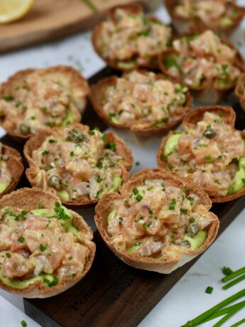 Tortilla Cups filled with creamy Avocado Mousse and topped with zesty Salmon Tartare, garnished with fresh chives