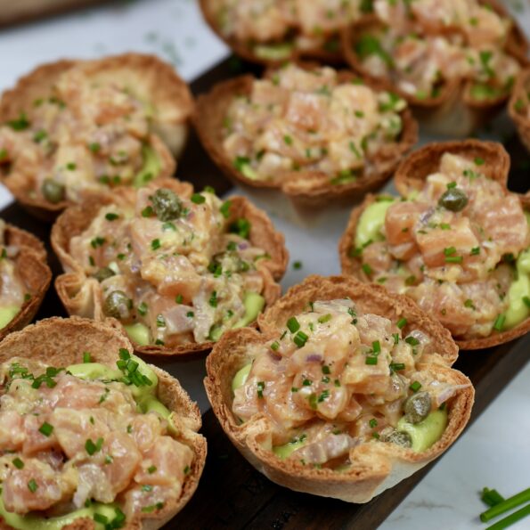 Tortilla Cups filled with creamy Avocado Mousse and topped with zesty Salmon Tartare, garnished with fresh chives