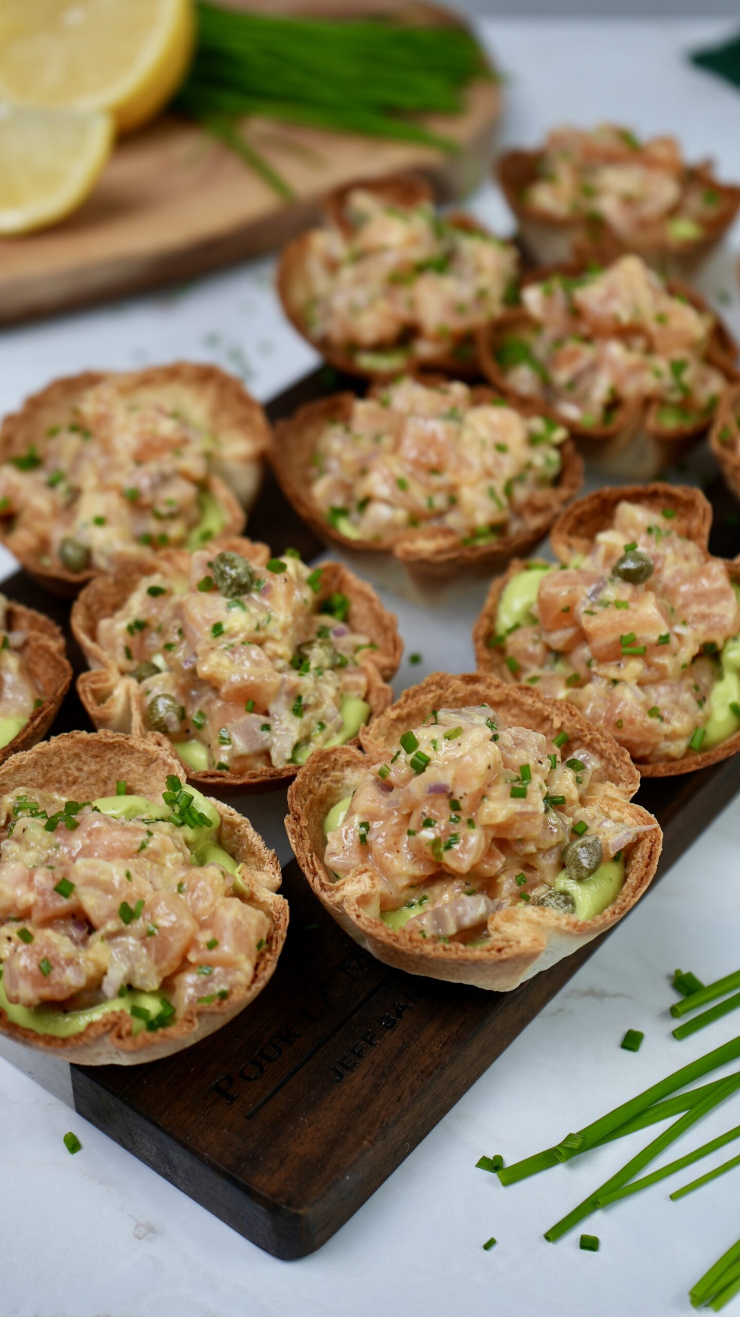 Tortilla Cups filled with creamy Avocado Mousse and topped with zesty Salmon Tartare, garnished with fresh chives