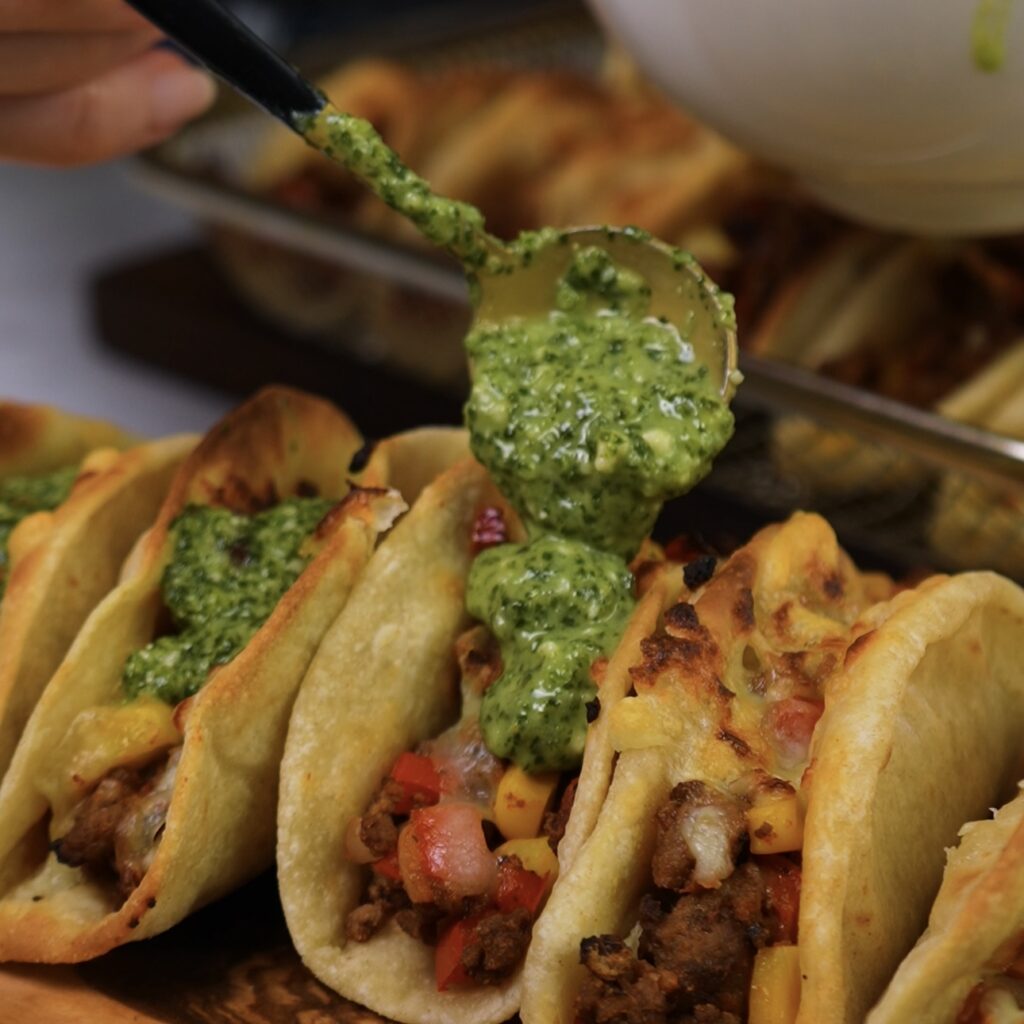 Drizzling Green Sauce Over Tacos