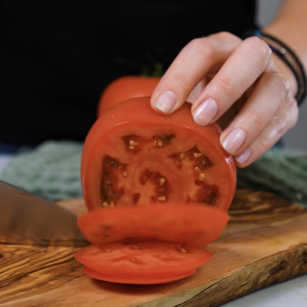 Slicing a ripe tomato on a cutting board.