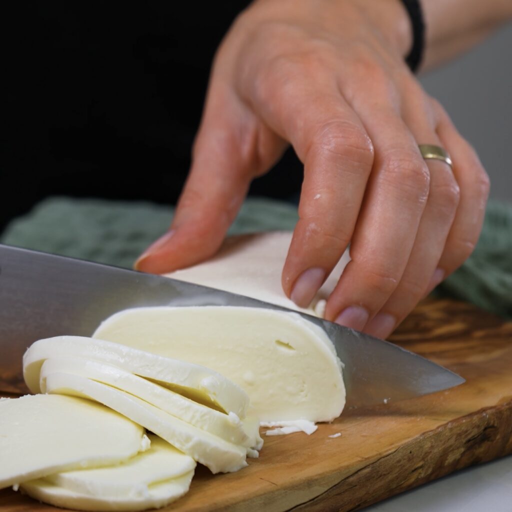 Slicing fresh mozzarella on a cutting board 