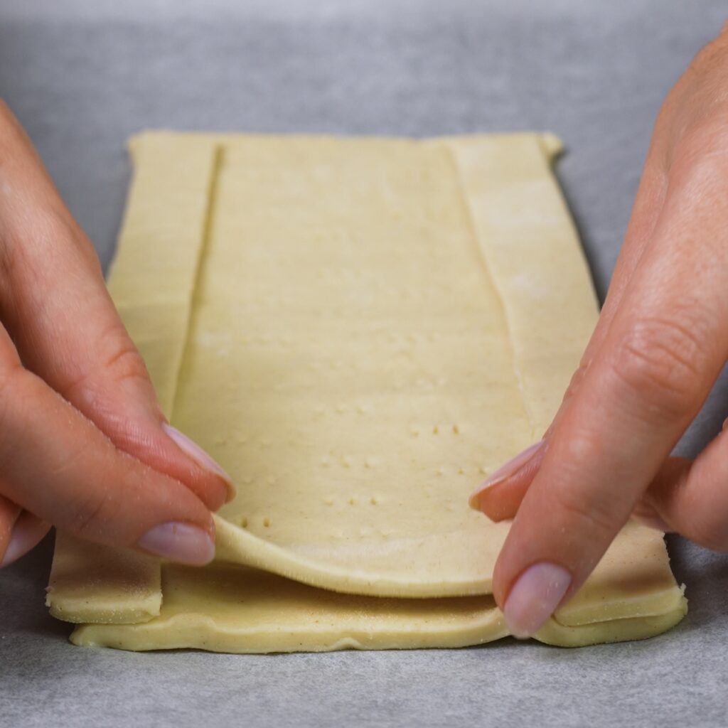 Creating a raised border by placing pastry strips on puff pastry rectangles to prepare Caprese tarts.