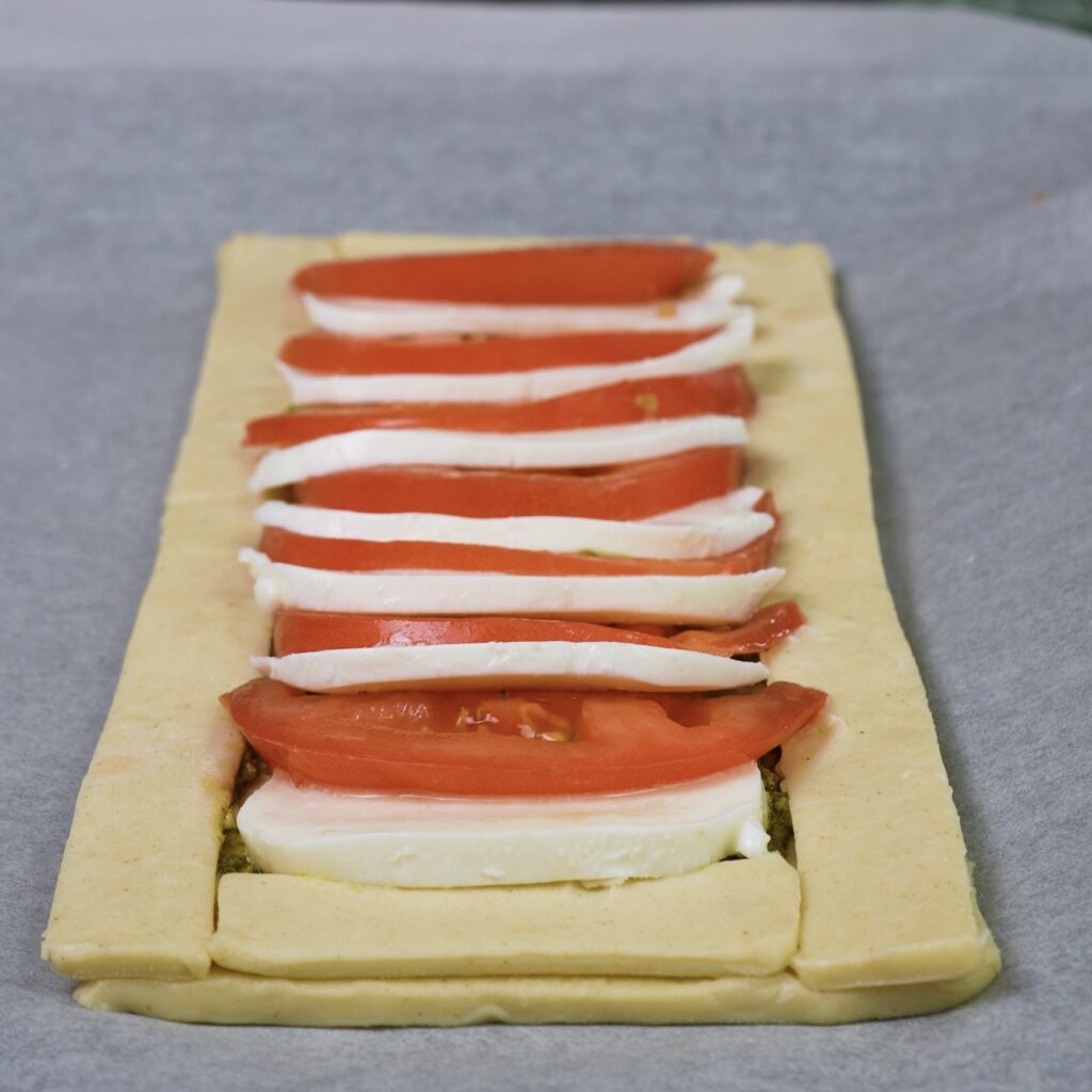 Assembling sliced tomatoes and mozzarella on puff pastry.