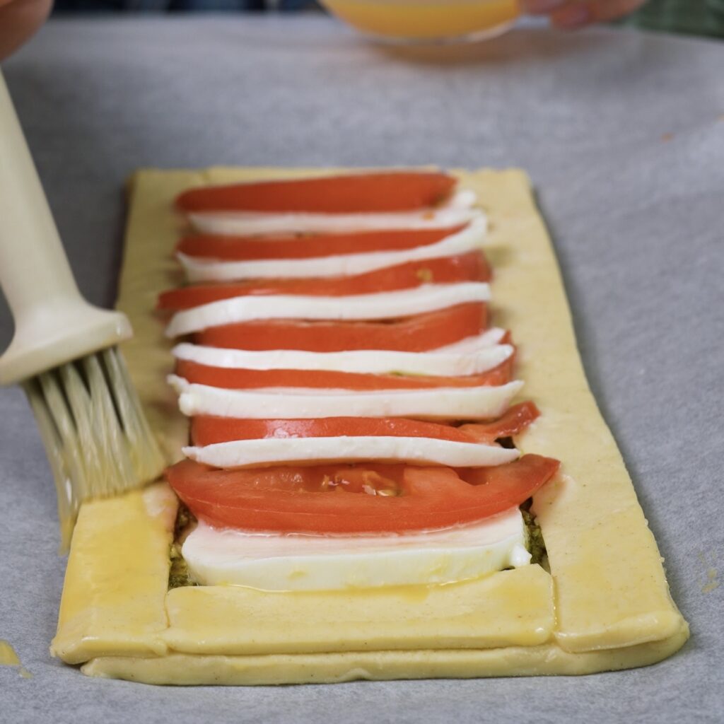 Brushing the edges of puff pastry with egg wash to give a golden finish