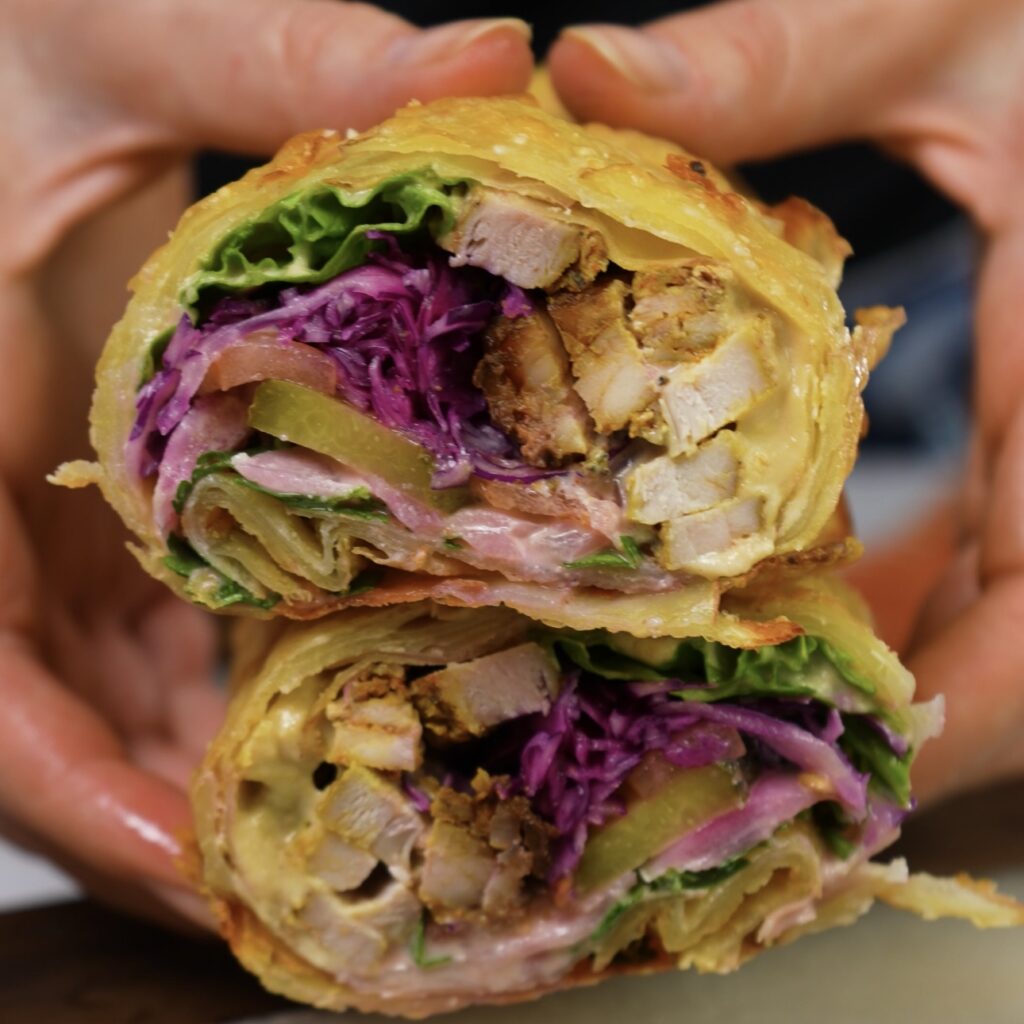 Halved Potato Wrap Shawarma revealing its flavourful filling of chicken shawarma, fresh vegetables, and hummus.