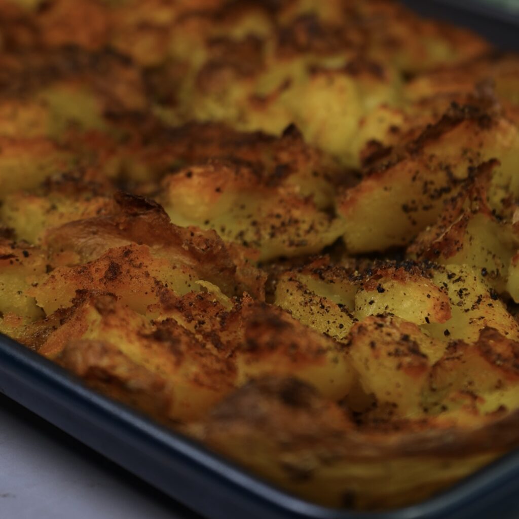 Roasted crushed potatoes on a baking tray, golden and crisp