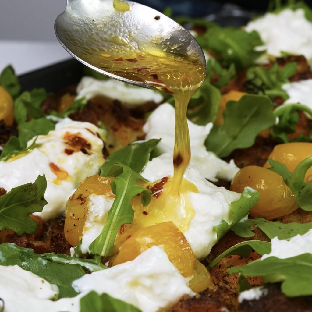 Drizzling tomato juice mixed with chilli flakes over Loaded Crushed Potatoes